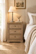 Sandy oak bedside chest with turned grey wood candlestick lamp in a linen bedroom