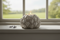 Stone artichoke tealight holder on a cottage windowsill with garden view
