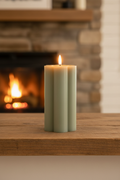 Tall sage green flower candle solo close up on a farmhouse mantel